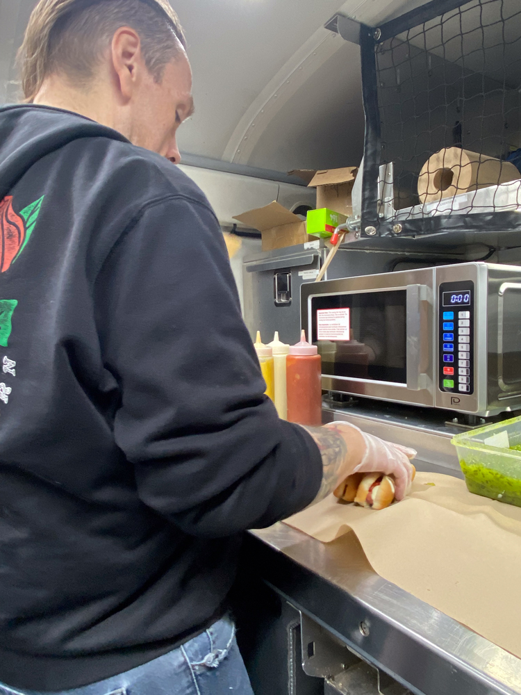 Patrick qui prépare des hot-dogs pour les jeunes à bord de la Roulotte